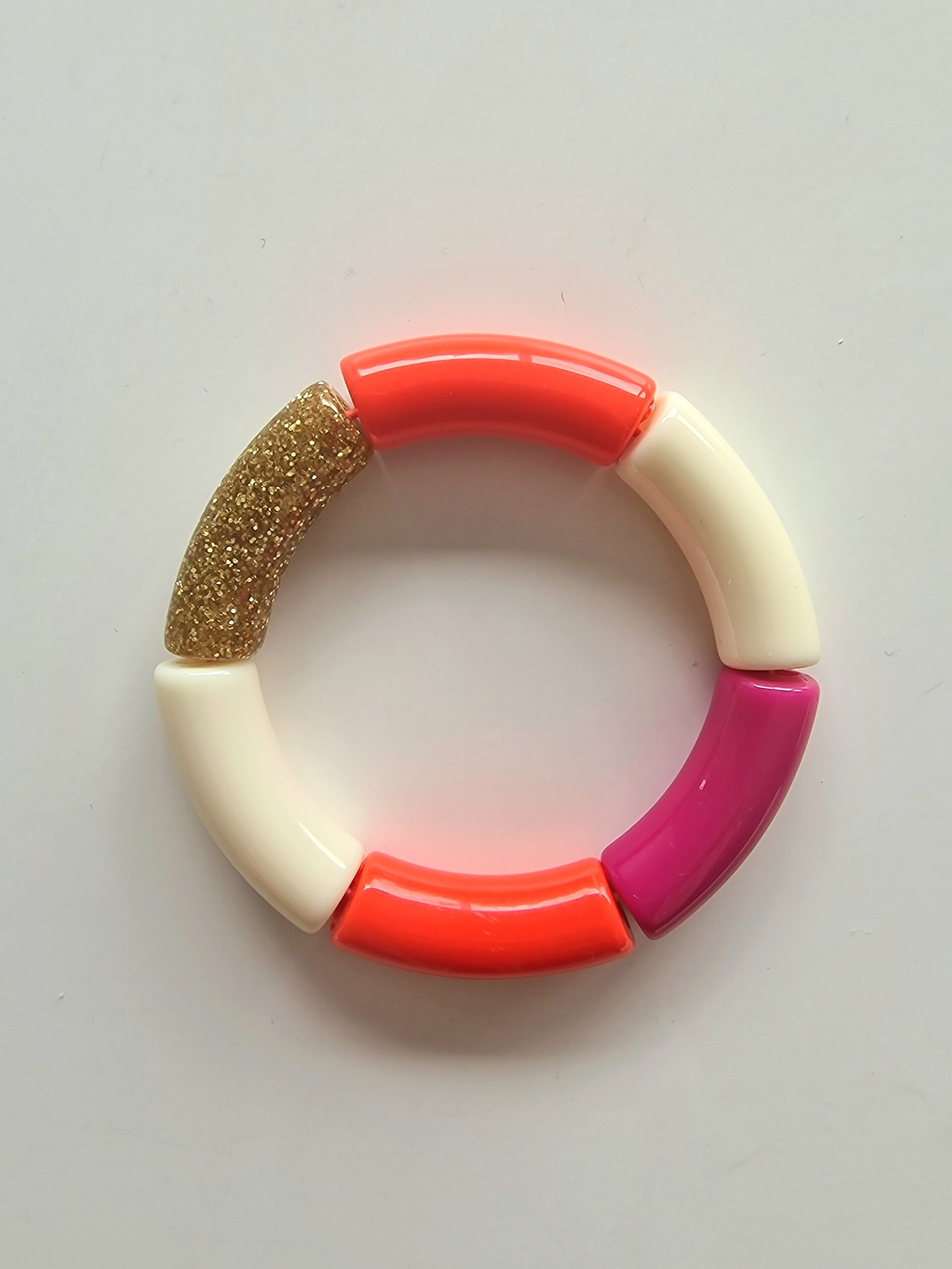Le bracelet rose est composé de 2 perles orange, une perle fuchsia, 2 perles blanches et 1 perle pailletée